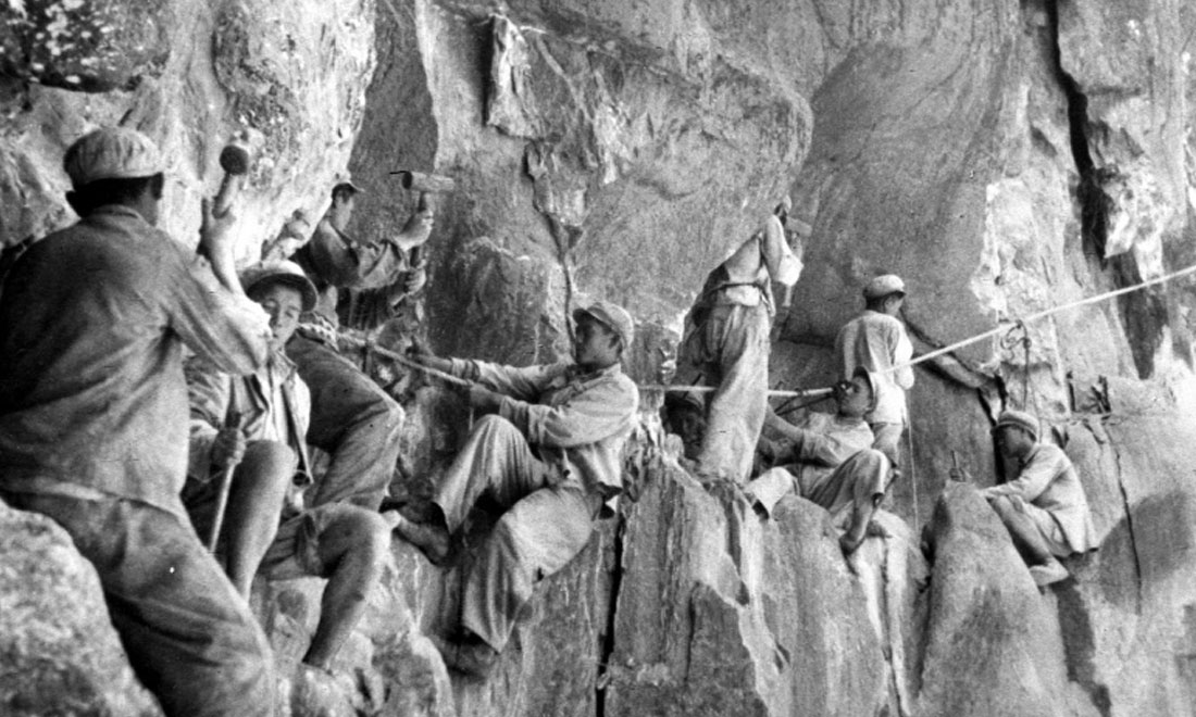 1954年，修筑康藏公路的解放軍戰(zhàn)士們?cè)谂瓋砂兜膽已露副谏媳偕街?。新華社稿 李萬春、張加里攝